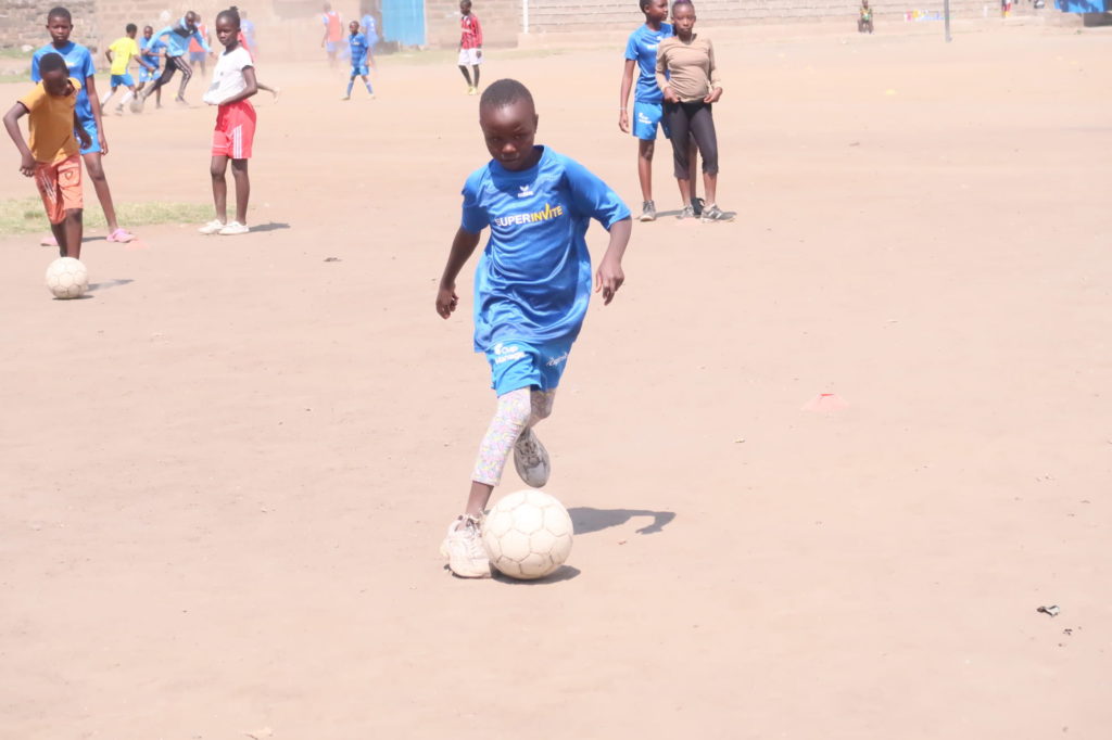 Boy wearing SuperInvite t-shirt playing football in Kenya