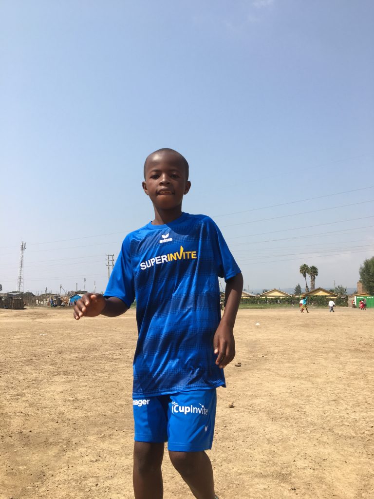 Boy wearing SuperInvite t-shirt playing football in Kenya