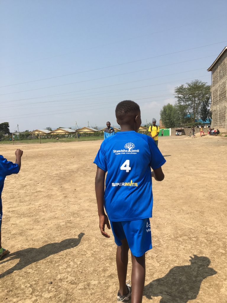 Boy wearing SuperInvite t-shirt playing football in Kenya