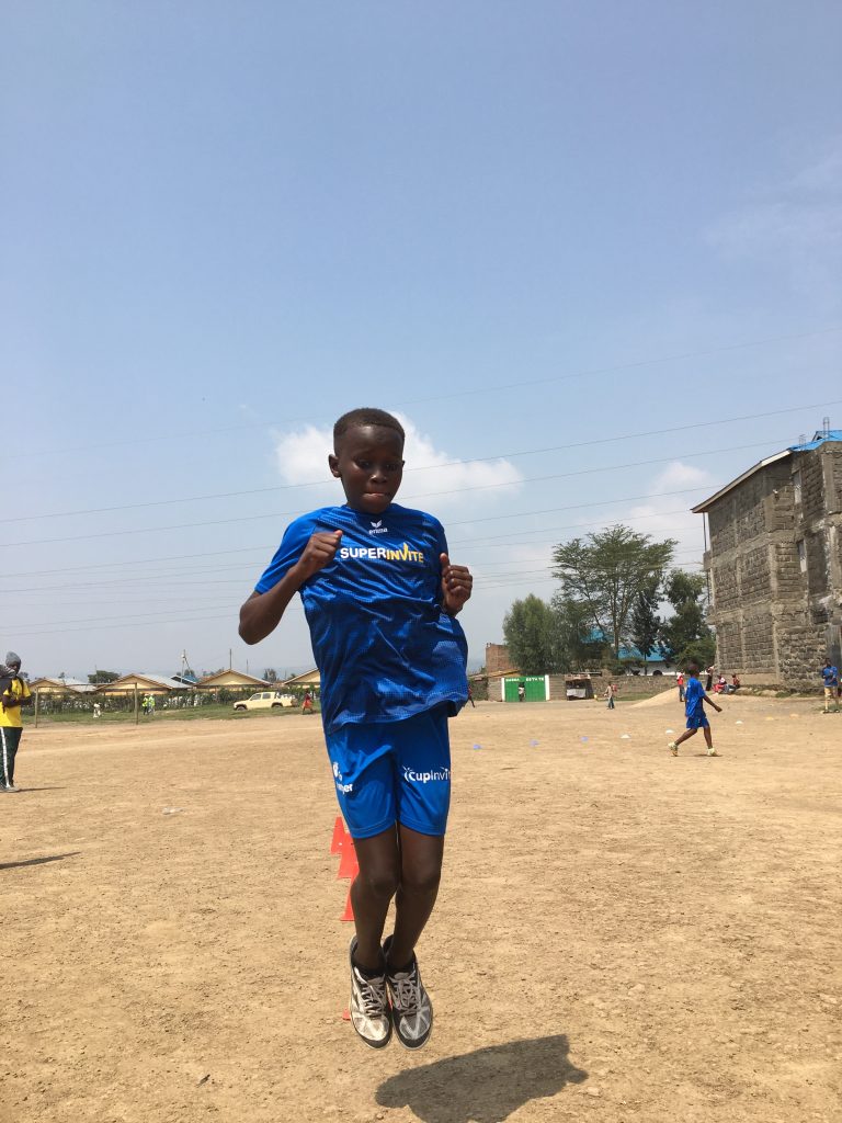 Boy wearing SuperInvite t-shirt playing football in Kenya