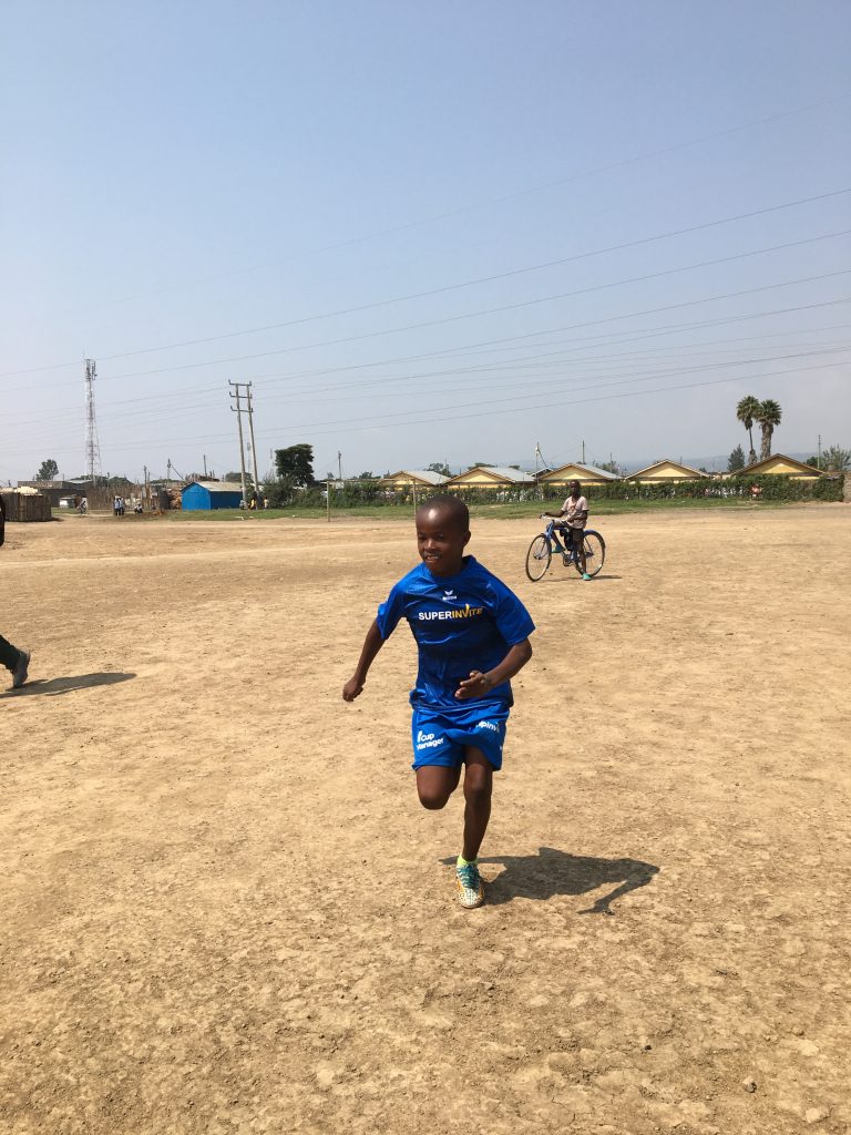 Boy wearing SuperInvite t-shirt playing football in Kenya