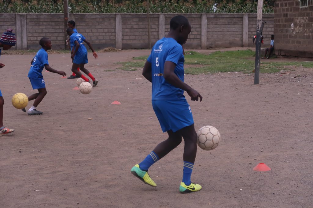 Boys wearing SuperInvite t-shirt playing football in Kenya