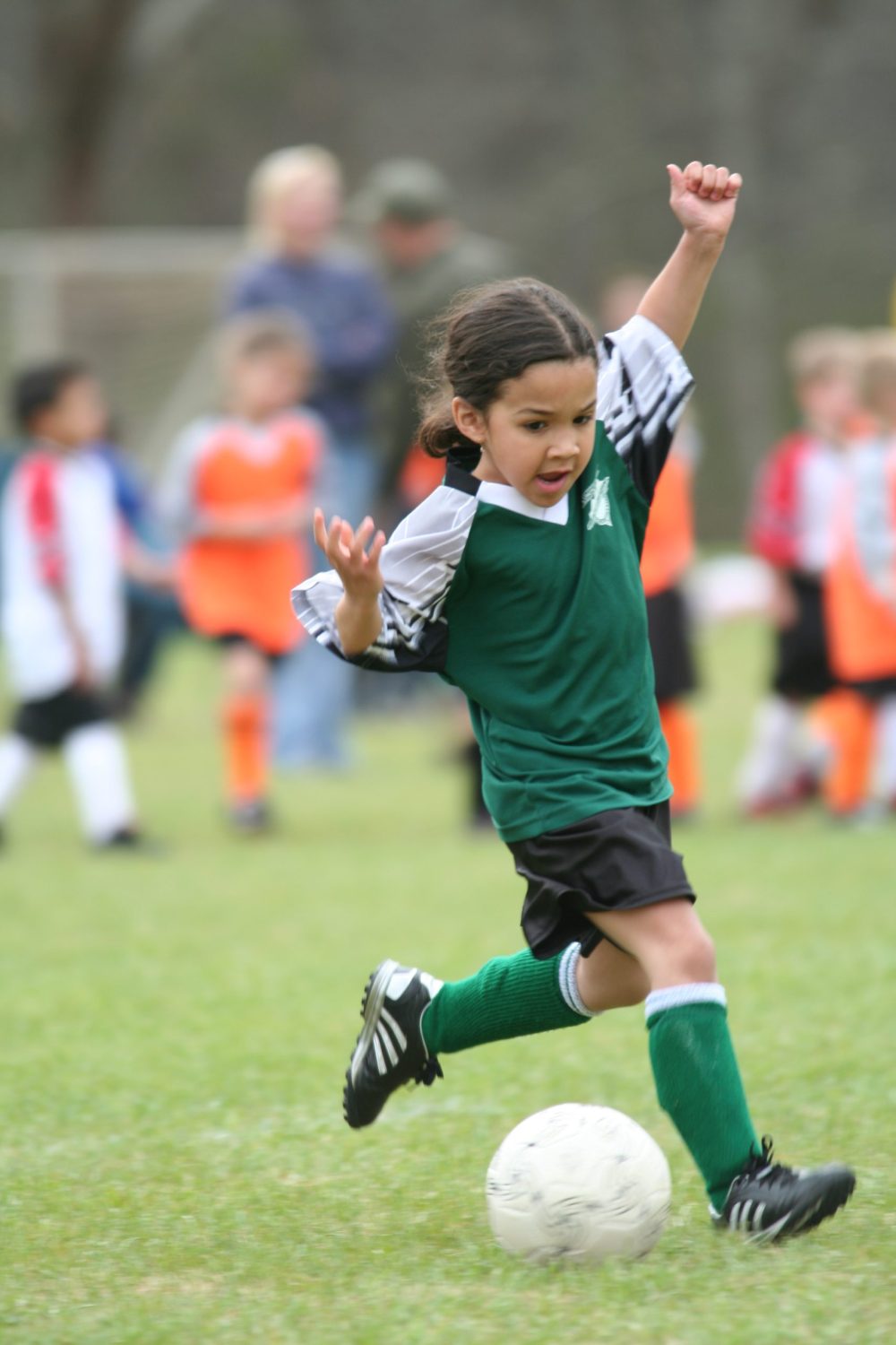 Boy dressed in green, playing football on the field