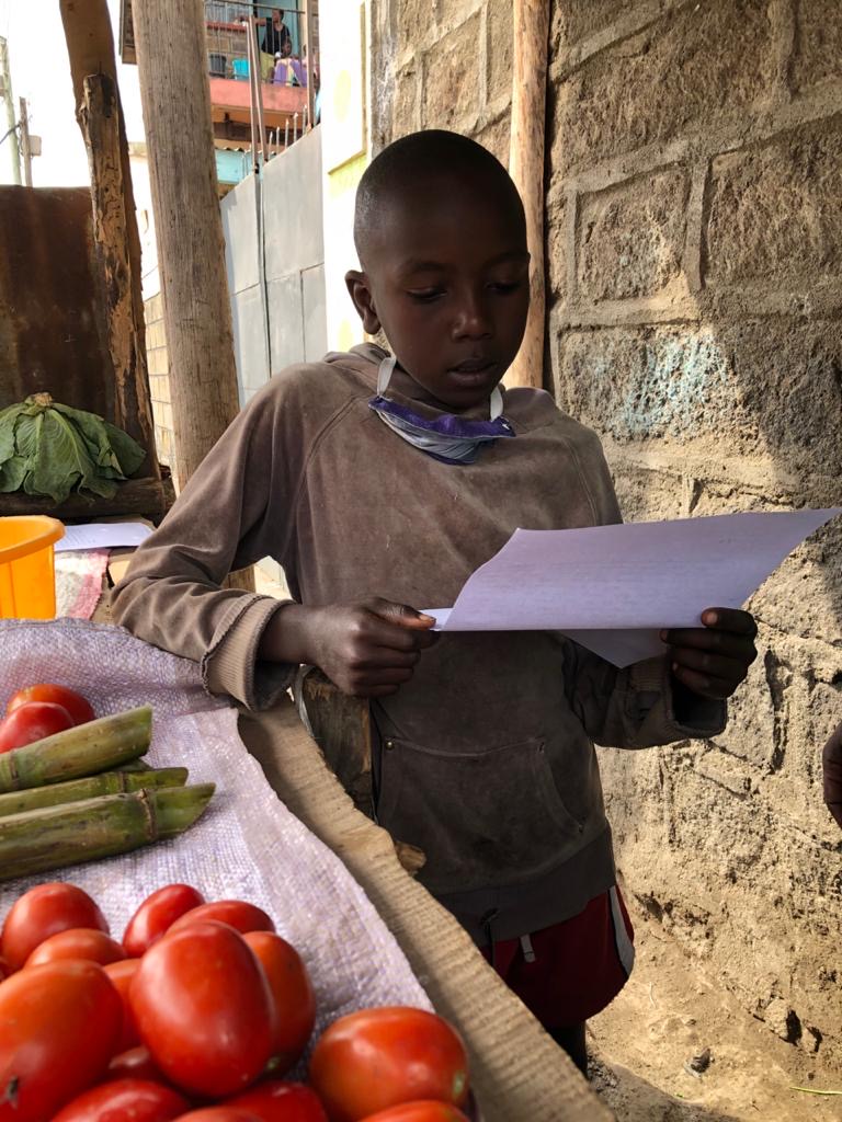 Boy at the market in Kenya, reading some letter